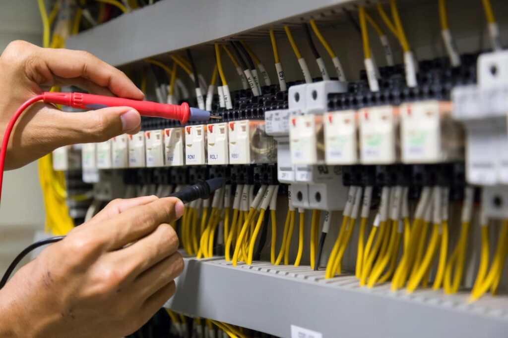 An electrician using soldering tools inside a bank of wiring